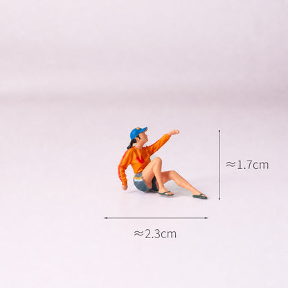 1:64 Everyday Street Scene Miniature Figure Series - Seated Woman in Orange Top Raising a Hand Figure